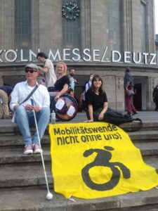 Gruppe mit Banner Mobilitätswende nicht ohne uns, ein Mensch mit Blindenstock