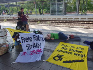 Menschen mit den Bannern auf dem Bahnsteig, eine Person liegt auf einer Isomatte