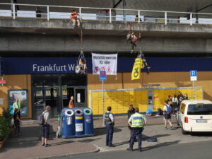 Überblicksaufnahme mit Banner 'Mobilitätswende für Alle' zwischen zwei kletternden rollstuhlfahrenden Menschen und 2 Kletter*innen